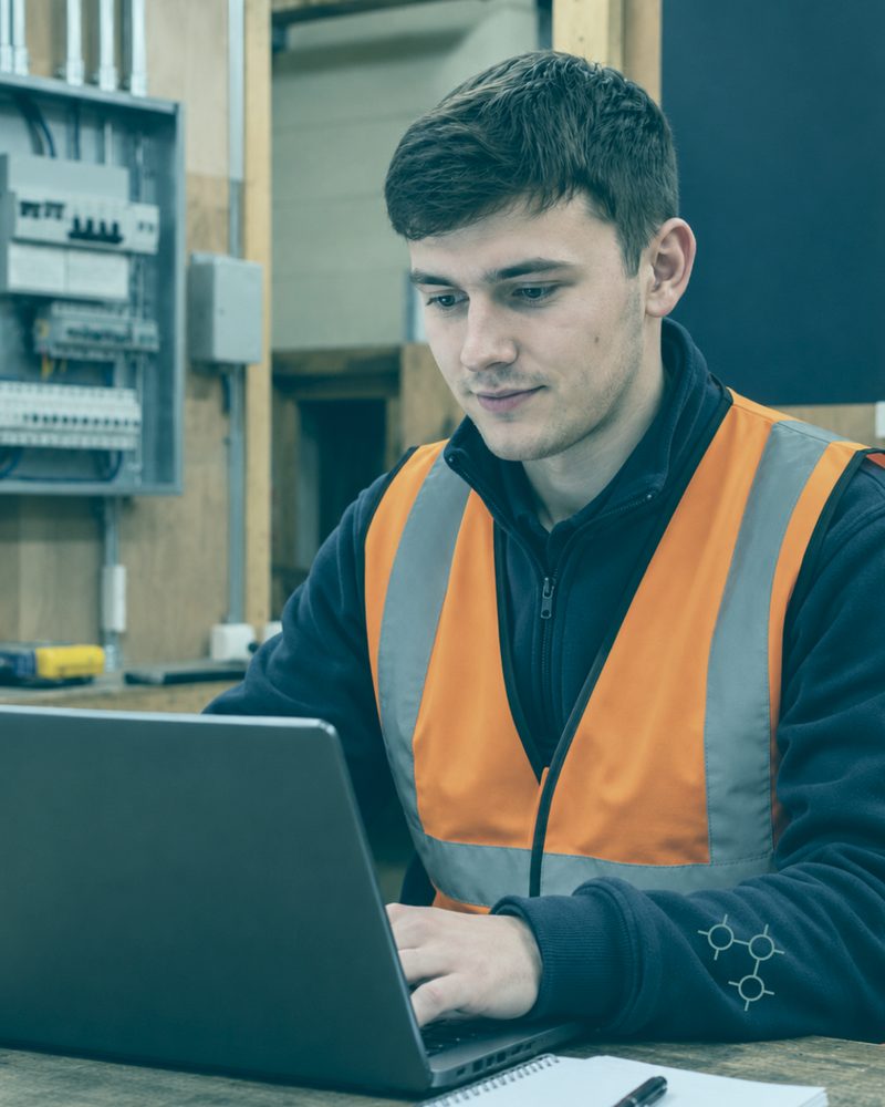 Technician in hi-vis completing the Bronze BASE Course on a laptop